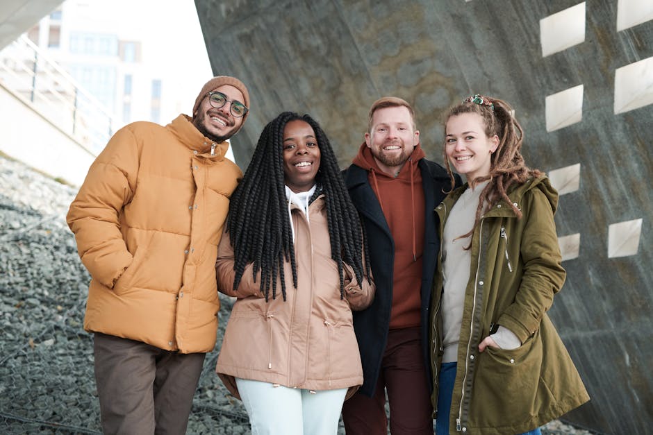 A group of four friends in winter attire smiling outdoors, enjoying togetherness.