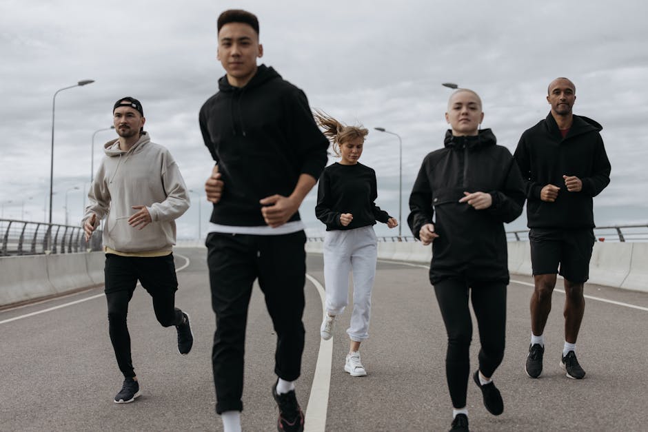 A diverse group of adults jogging together outdoors on a cloudy day.