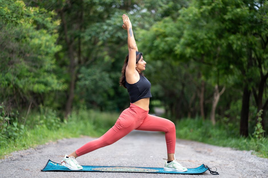 A woman practicing yoga outdoors in a vibrant forest, showcasing health and wellness.