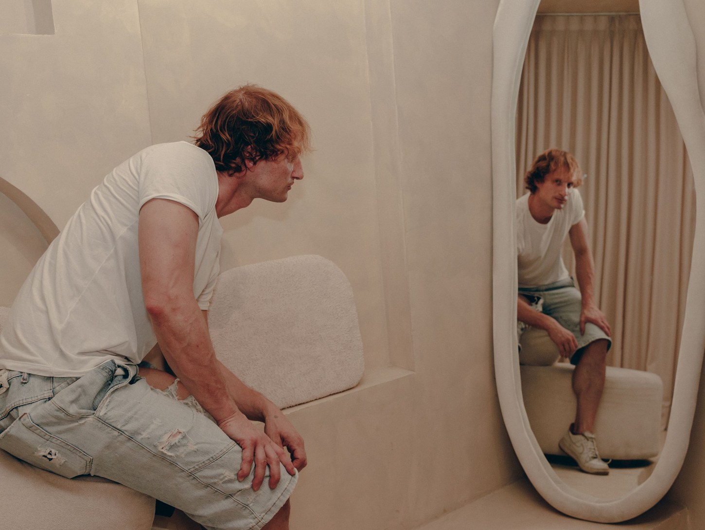 Man sitting near a mirror while checking his outfit