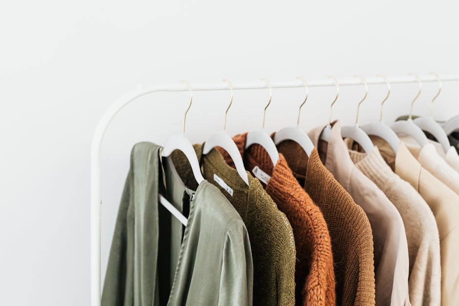 A minimalist display of colorful sweaters and shirts on white hangers.