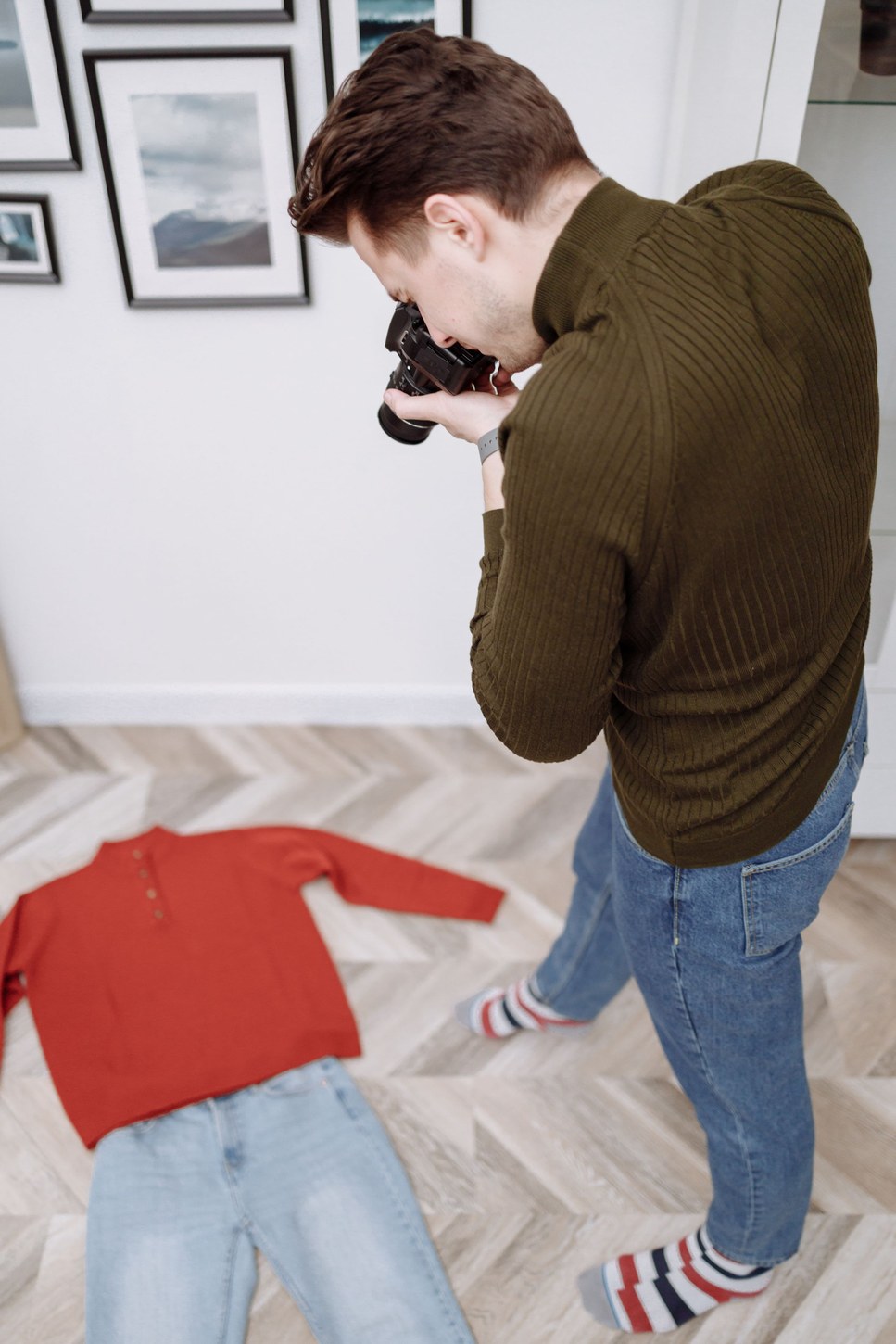 Man photographing casual clothes laid out on the floor