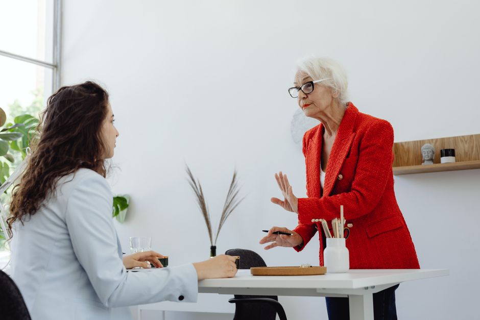 Two women engage in a professional discussion in a modern office setting.