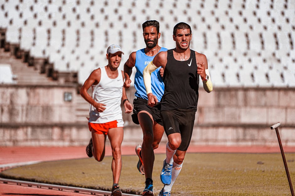 Three male athletes competing in an intense outdoor running race on a track.