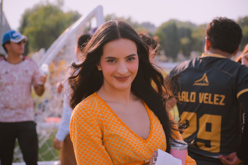Cheerful young woman in a yellow dress enjoying an outdoor gathering in sunny weather.