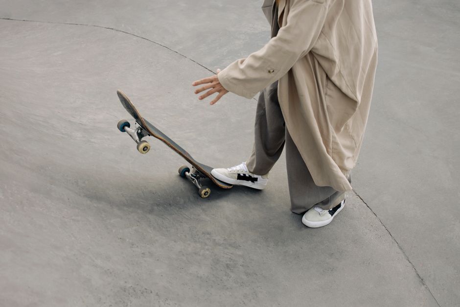 A modern skateboarding scene featuring a stylish individual in a long trench coat at the skate park.