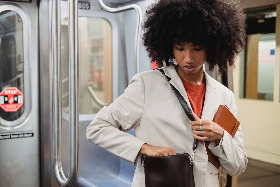 Young woman with afro hair on subway, holding a book and adjusting her bag.