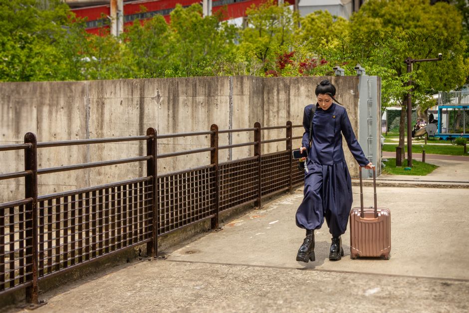 Stylish woman walking with suitcase in urban Shanghai, showcasing modern travel lifestyle.