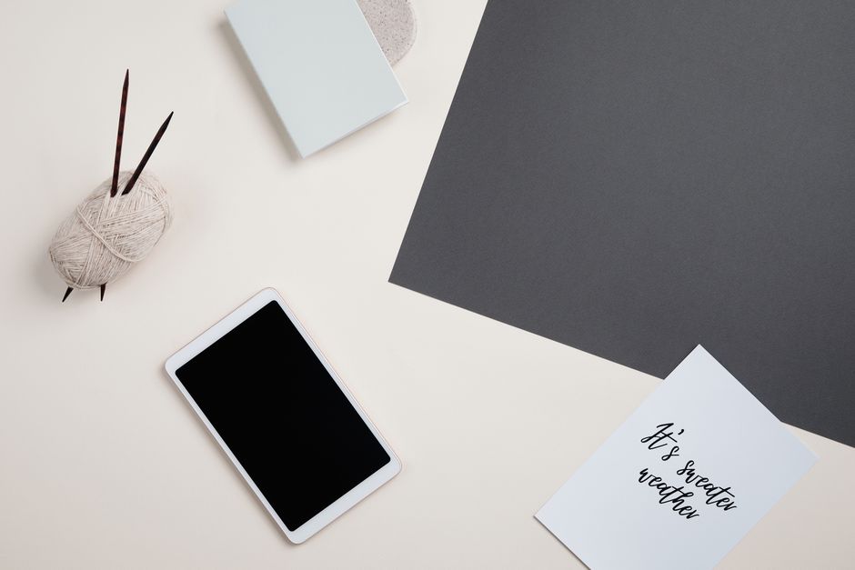 Flat lay of a digital tablet, yarn, and paper for creative and cozy projects.