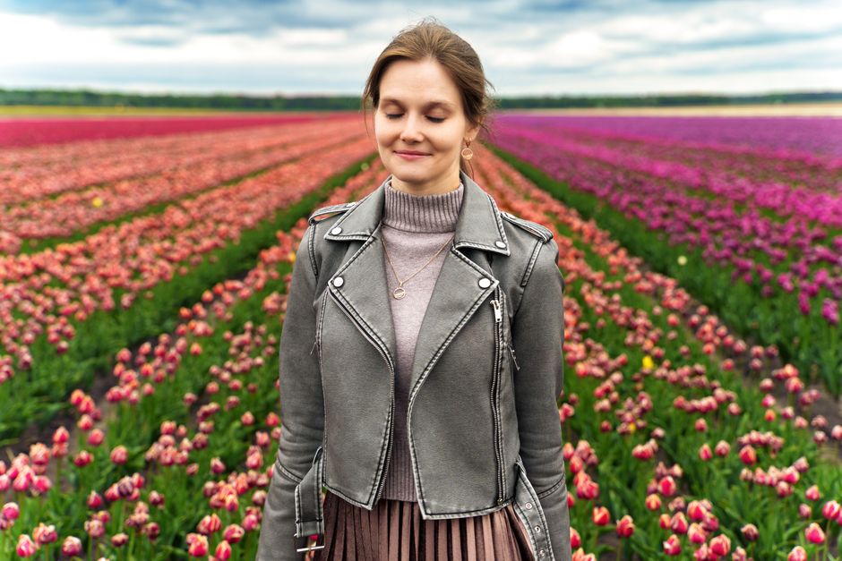 A woman enjoys a peaceful moment amid a colorful tulip field in spring.