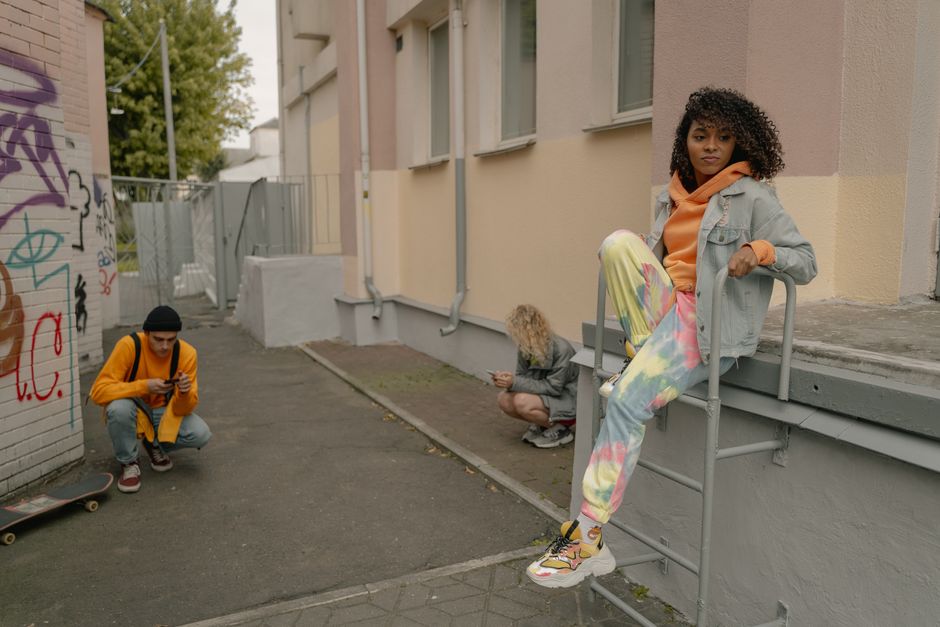 Casual urban scene with friends relaxing and taking photos against a graffiti wall.