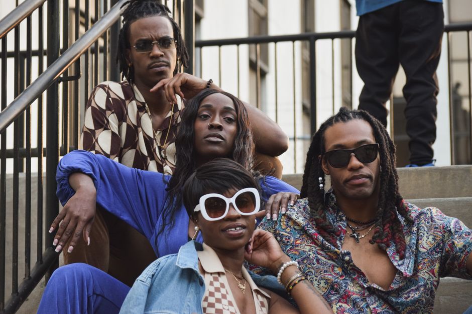 A stylish group of adults in trendy attire posing on steps outdoors.