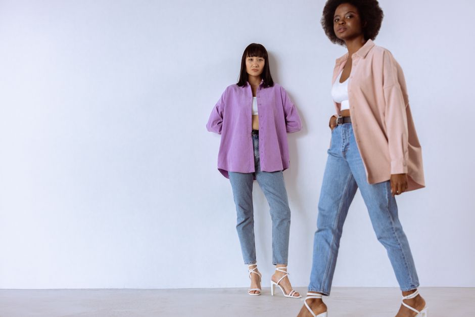 Stylish portrait of diverse women wearing trendy outfits with unbuttoned shirts in a studio setting.