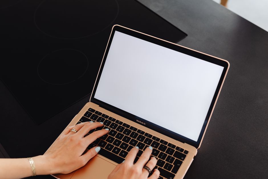 Hands typing on a laptop with a blank screen, perfect for mockup or design presentations.